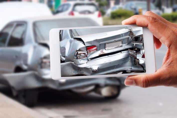 A person taking a photo of the damage to their car after an accident.